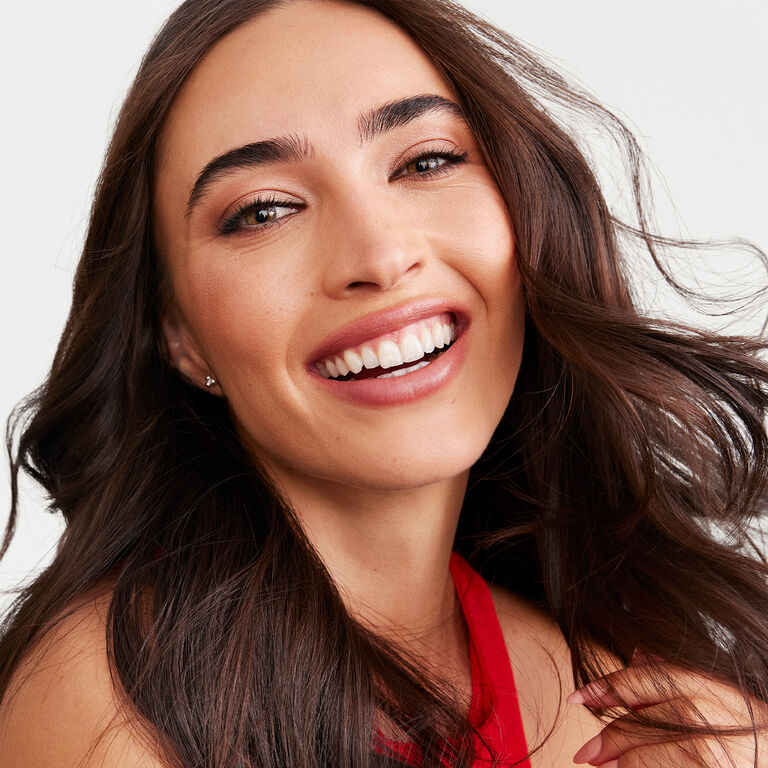 A brunette model wearing the Saharan Dusk look appears smiling