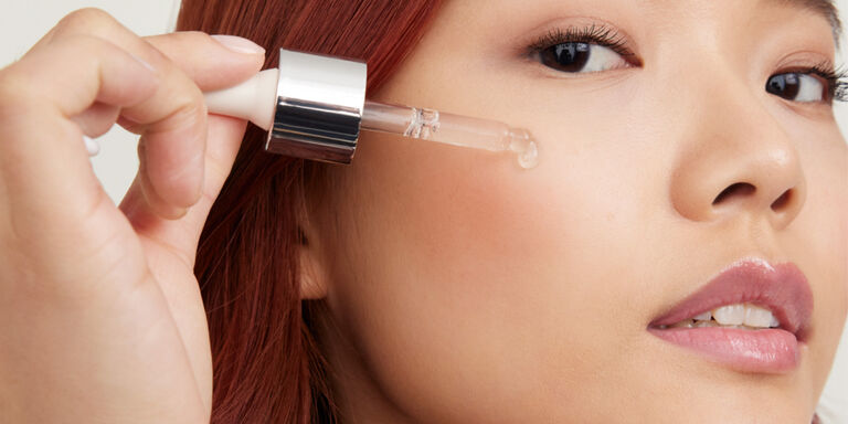 Model applying serum with dropper to cheek
